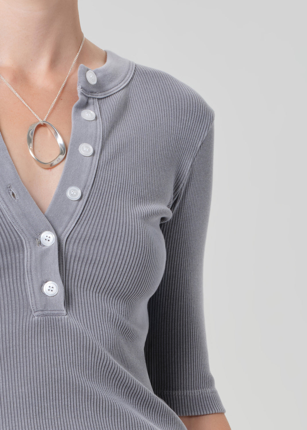 Gray ribbed sweater with button details on a plain background