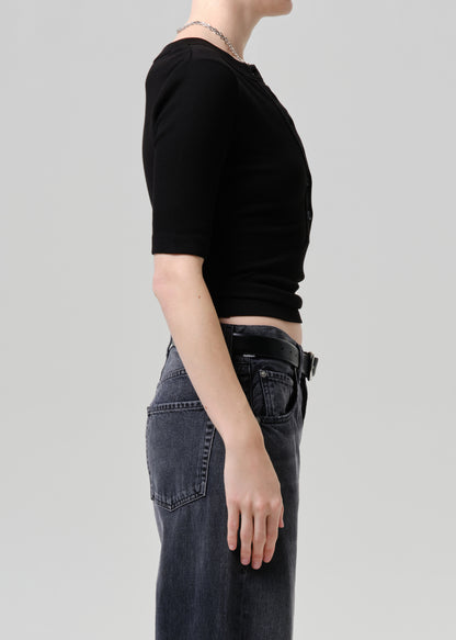 Person wearing a black crop top and dark jeans on a plain background