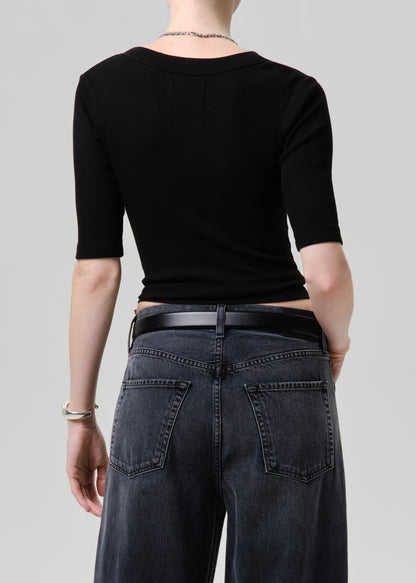 Person wearing a black crop top and dark jeans on a plain background