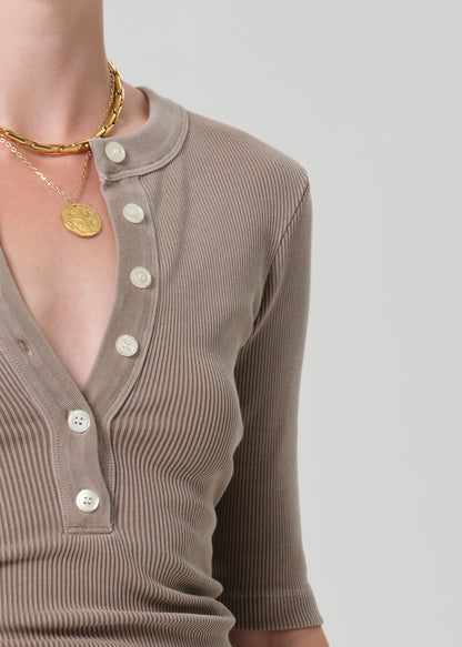 Brown ribbed sweater with buttons on a plain background
