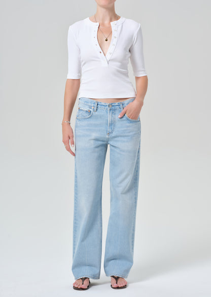 Person wearing a white short-sleeve shirt and light blue jeans on a gray background