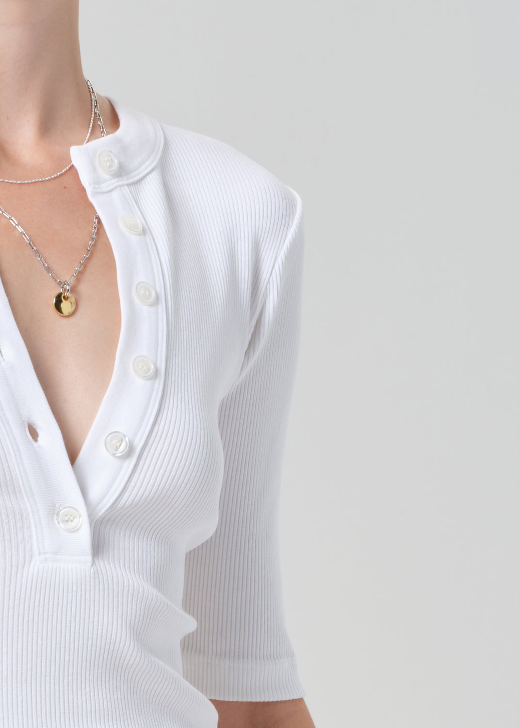 White ribbed top with a deep neckline worn by a person on a light gray background