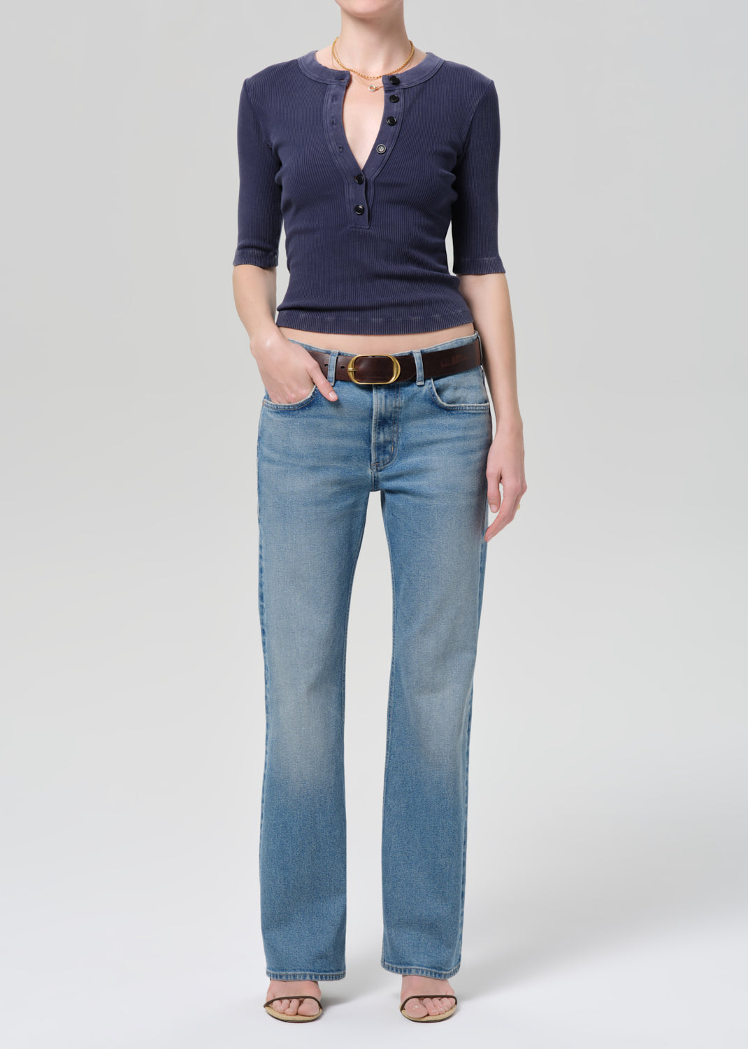 Person wearing a navy blue shirt and light blue jeans on a plain background