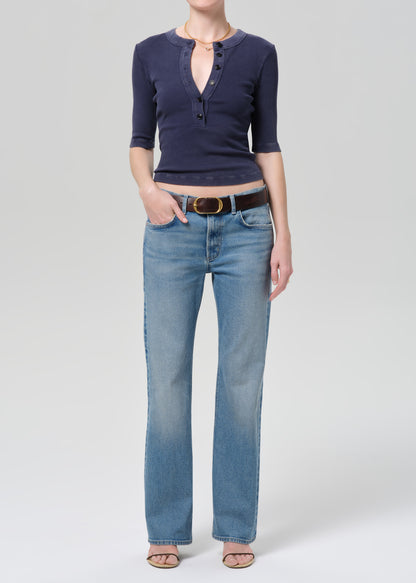 Person wearing a navy blue shirt and light blue jeans on a plain background