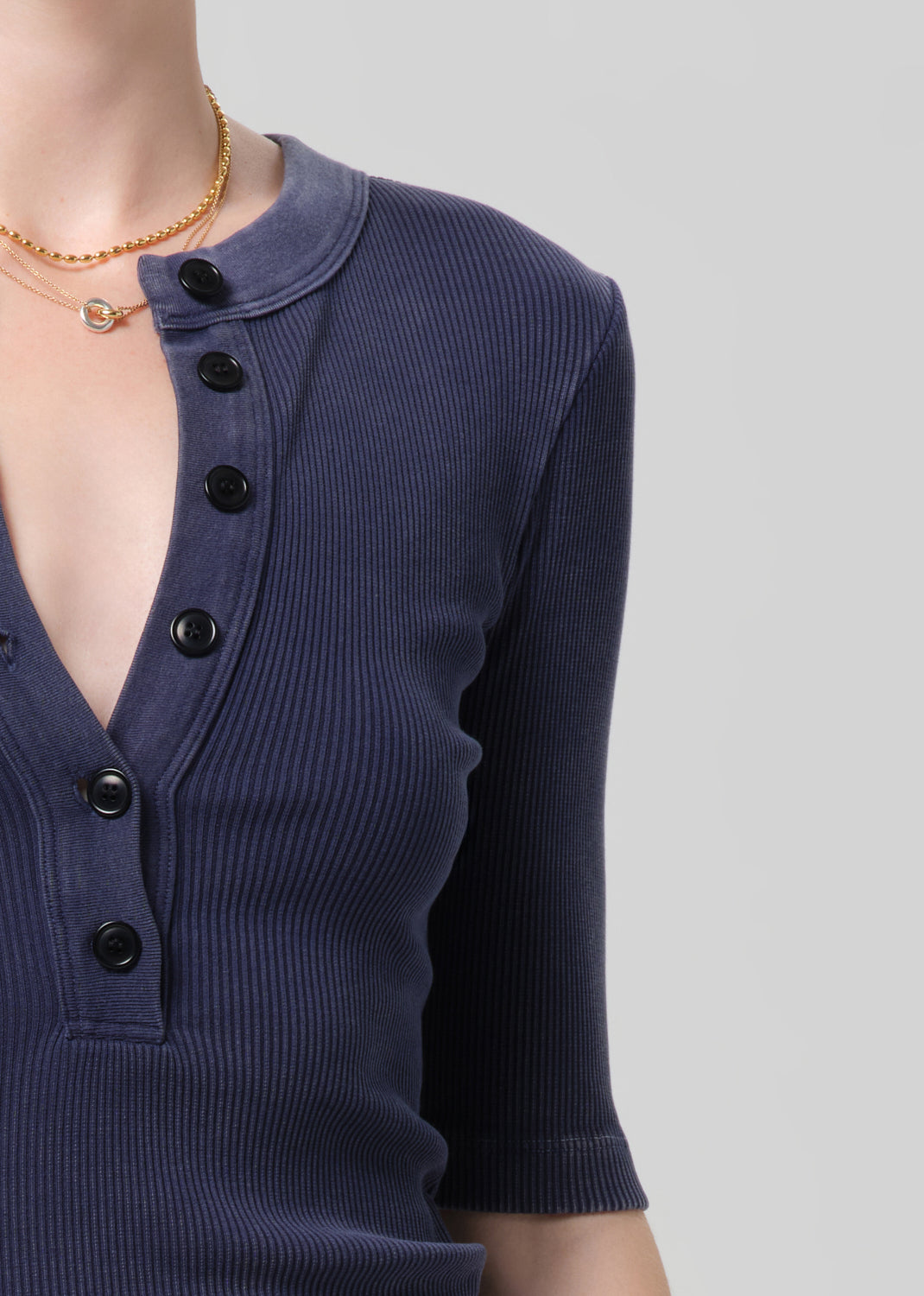 Navy blue ribbed sweater with black buttons on a plain background