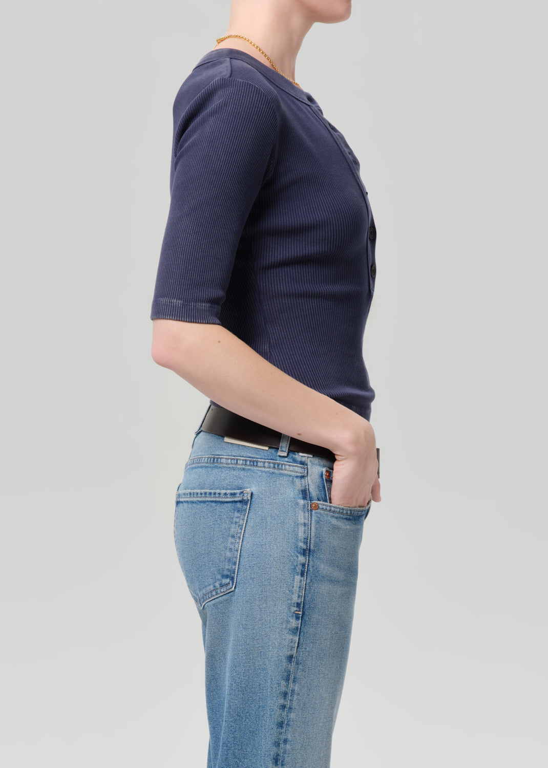 Person wearing a navy blue t-shirt and light blue jeans on a gray background
