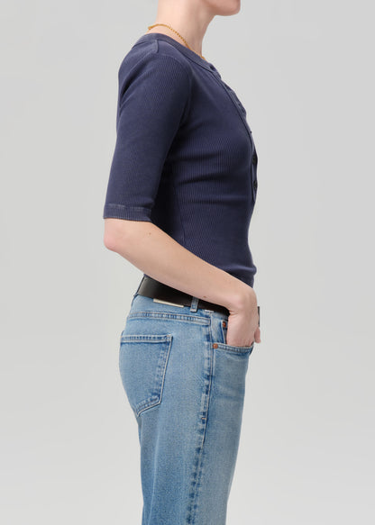 Person wearing a navy blue t-shirt and light blue jeans on a gray background