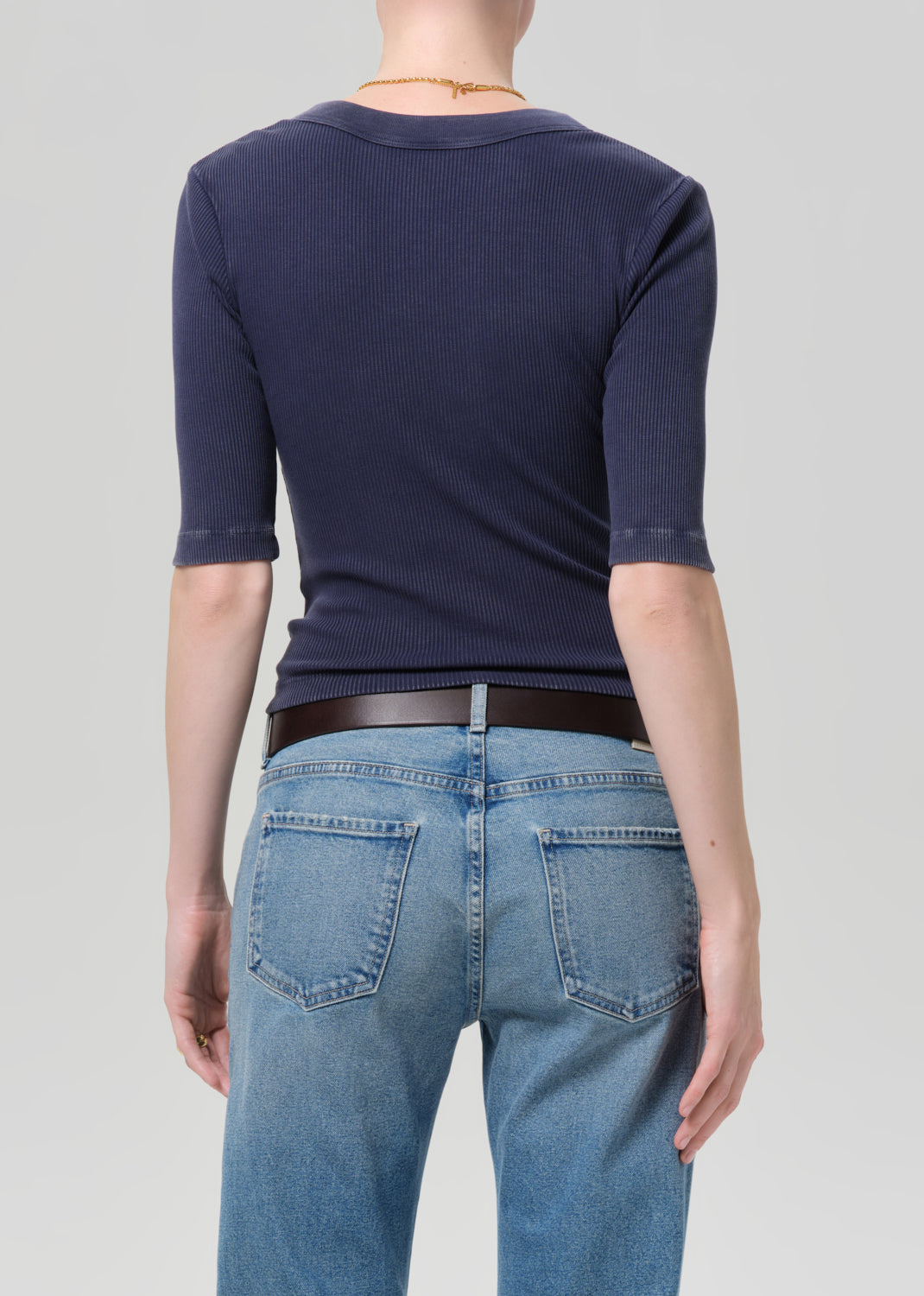 Person wearing a navy blue shirt and blue jeans on a plain background