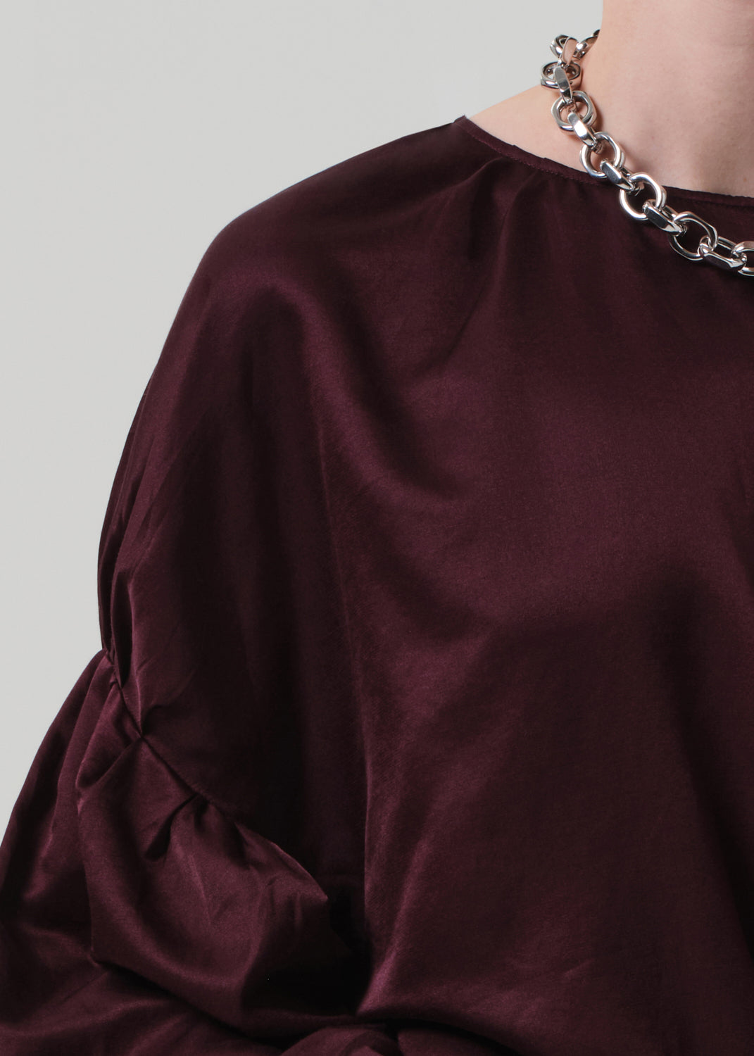 Close-up of a burgundy dress with a chain necklace on a plain background