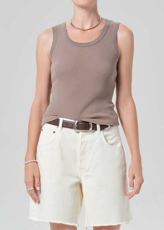 Person wearing a brown tank top and white shorts on a plain background