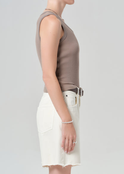 Person wearing a brown tank top and white shorts on a plain background