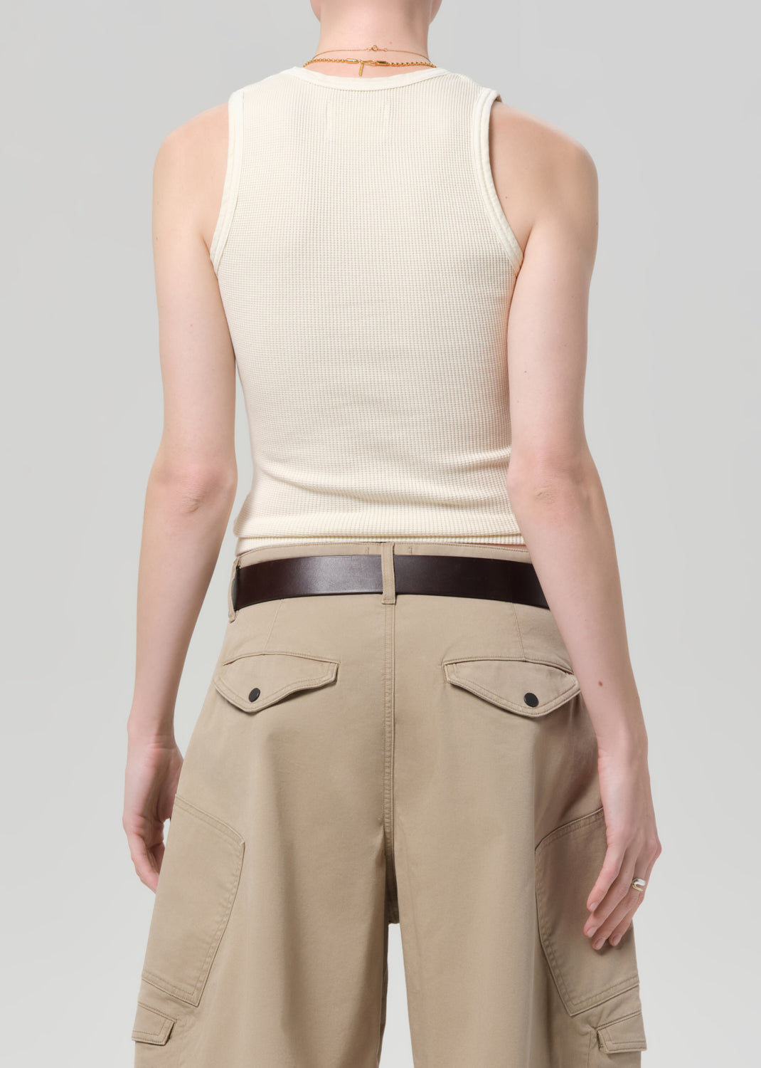 Person wearing a beige sleeveless top and beige cargo pants on a light gray background