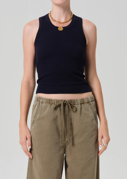 Person wearing a black sleeveless top and khaki pants on a plain background