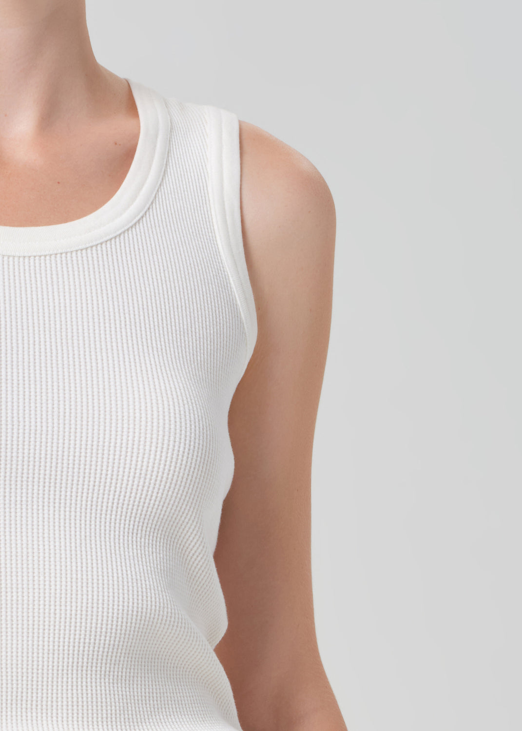 White sleeveless top worn by a person on a light gray background