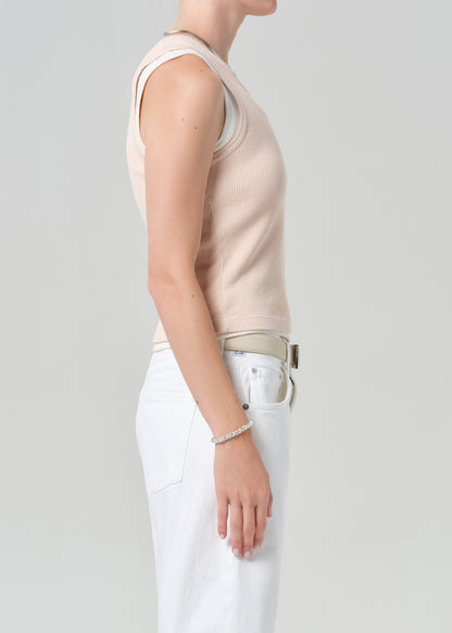 Person wearing a pink sleeveless top and white shorts on a plain background