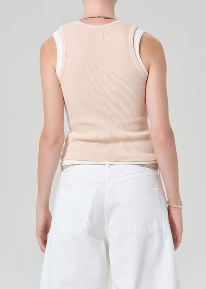 Person wearing a pink sleeveless top and white shorts on a plain background