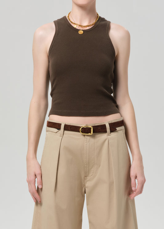 Person wearing a brown sleeveless top and beige pants with a belt on a gray background