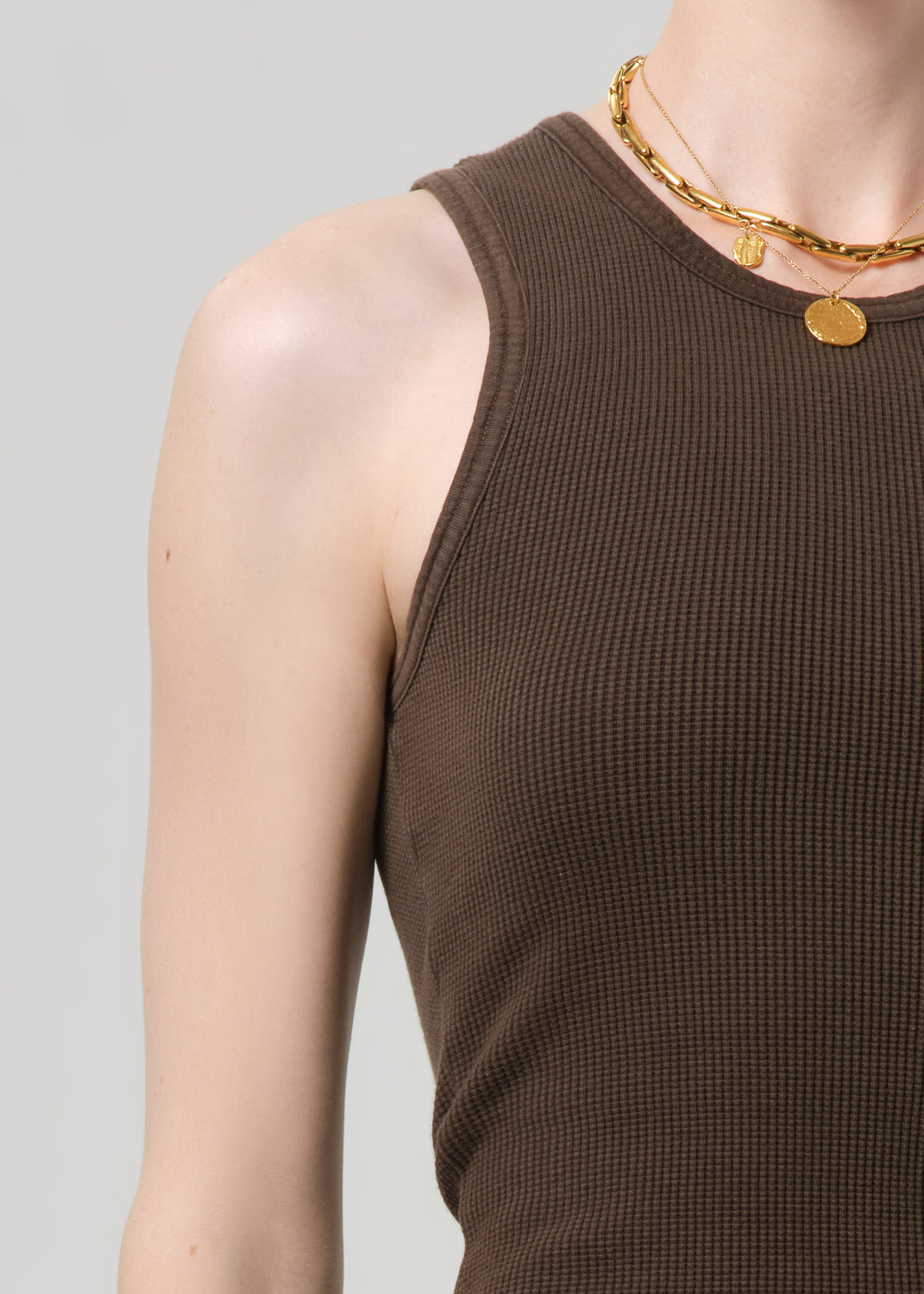 Brown ribbed tank top worn by a person on a gray background