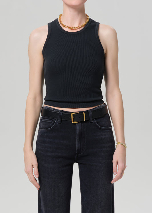 Person wearing a black tank top and black jeans on a grey background