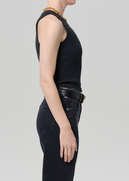 Person wearing a black tank top and black jeans on a grey background