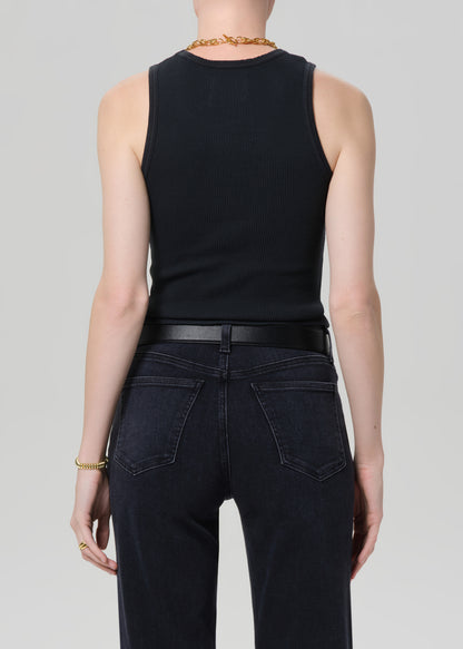 Person wearing a black tank top and black jeans on a grey background