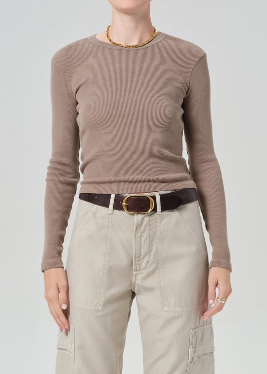 Person wearing a brown ribbed long-sleeve top and beige cargo pants with a belt on a plain background