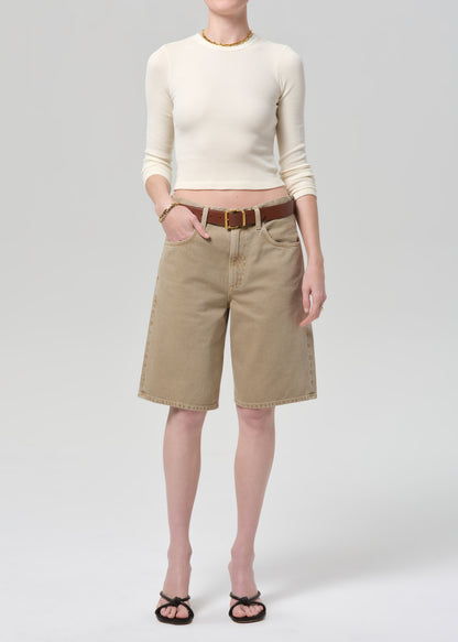 Person wearing a cream top and beige shorts on a plain background