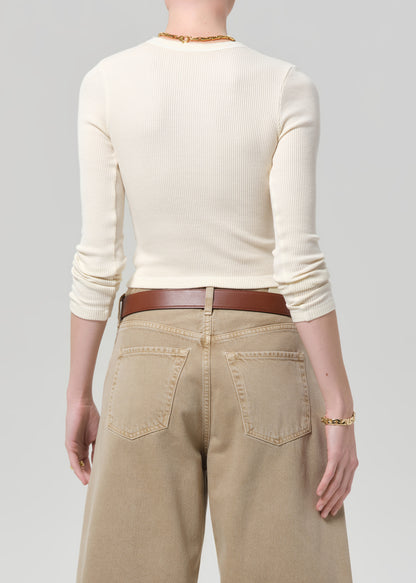 Person wearing a cream top and beige pants on a gray background