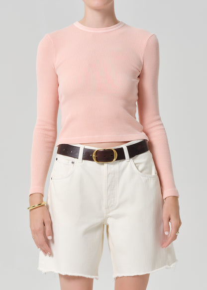 Person wearing a pink top with cream denim shorts