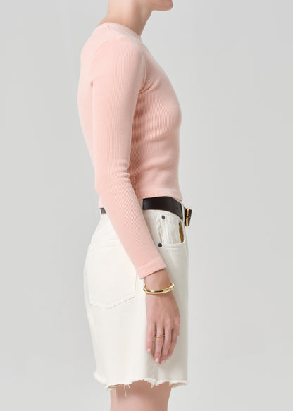 Person wearing a pink top with cream denim shorts