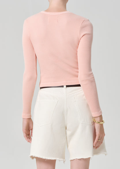 Person wearing a pink top with cream denim shorts