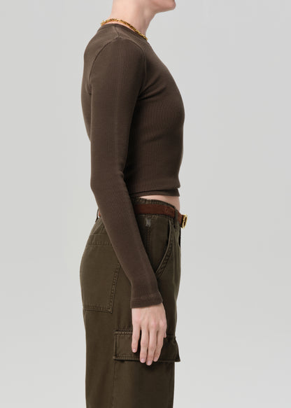 Person wearing a brown long-sleeve top and brown pants on a light gray background