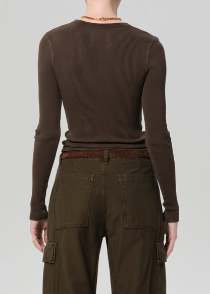 Person wearing a brown long-sleeve top and cargo pants on a plain background
