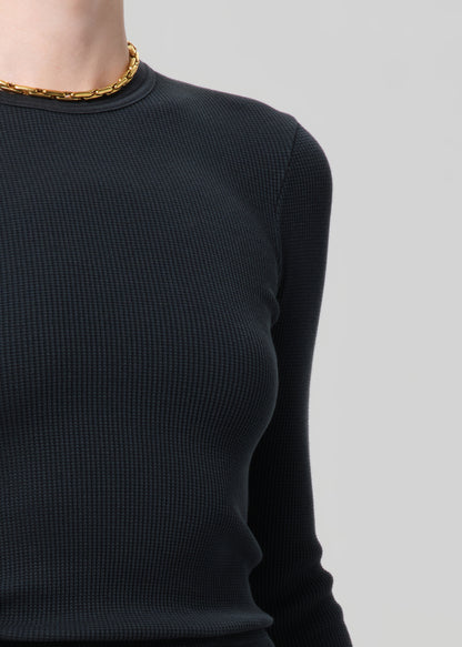 Black long-sleeve top worn by a person on a light gray background