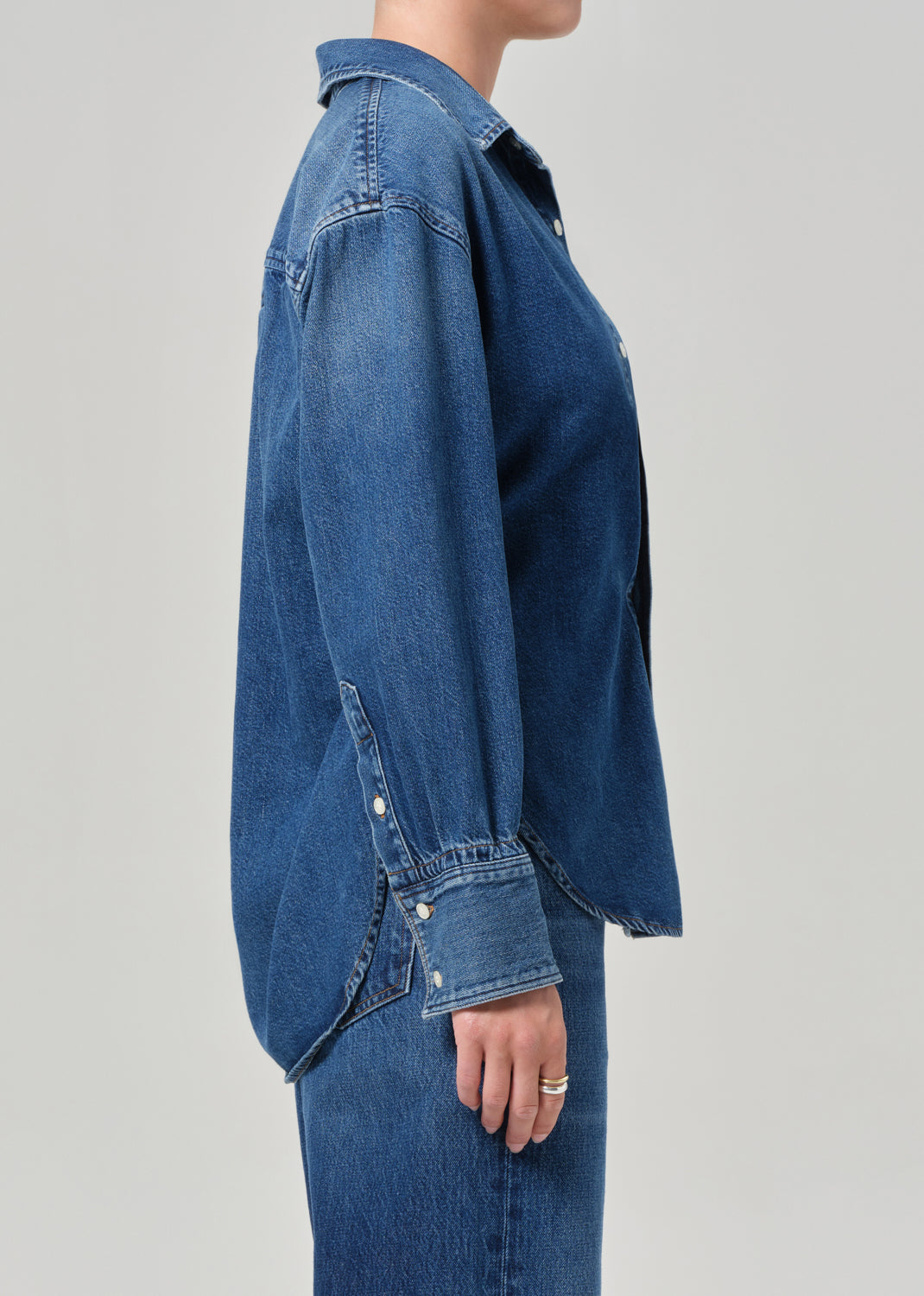 Person wearing a blue denim shirt on a gray background