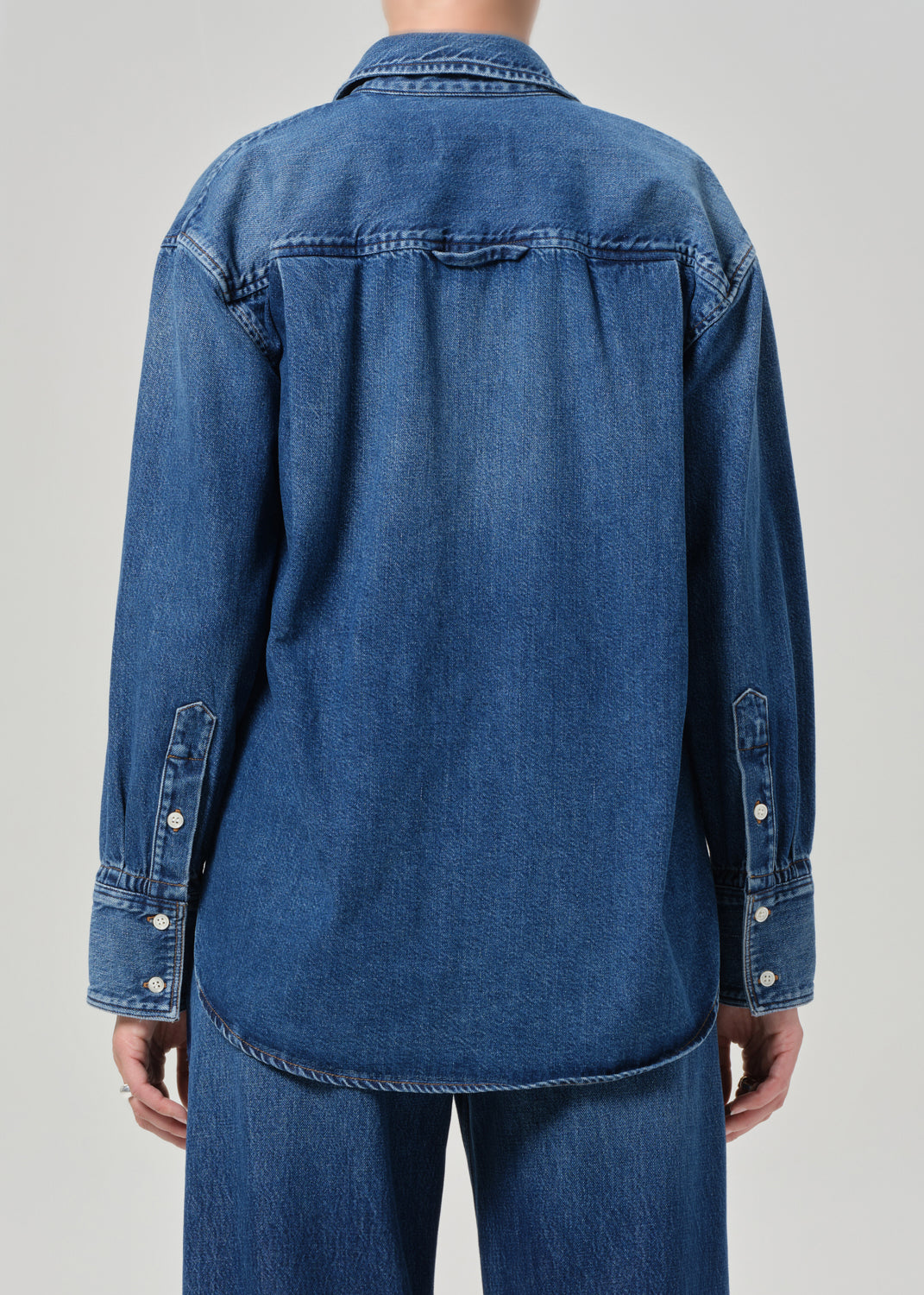 Blue denim shirt worn by a person on a gray background