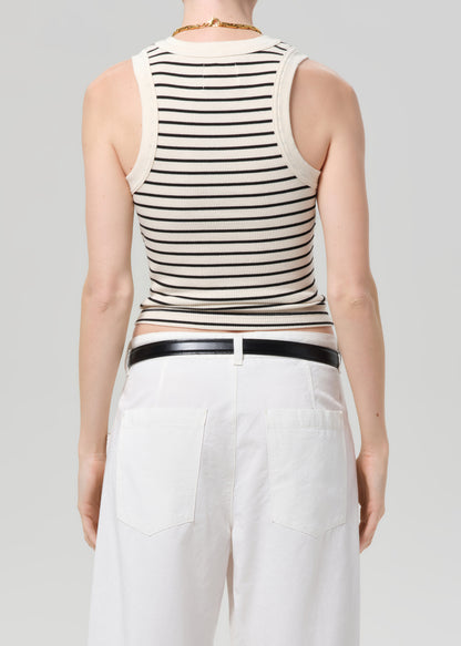 Person wearing a striped sleeveless top and white pants on a plain background