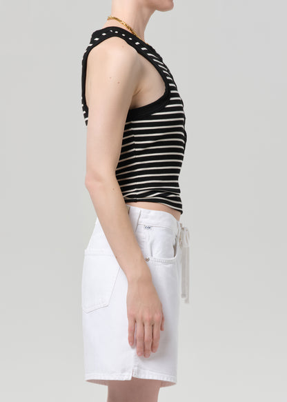 Person wearing a black and white striped sleeveless top with a deep neckline and white shorts on a gray background.