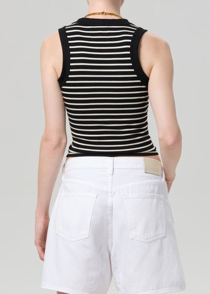 Person wearing a black and white striped sleeveless top with a deep neckline and white shorts on a gray background.