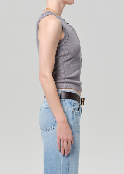 Person wearing a gray tank top and blue jeans on a light gray background