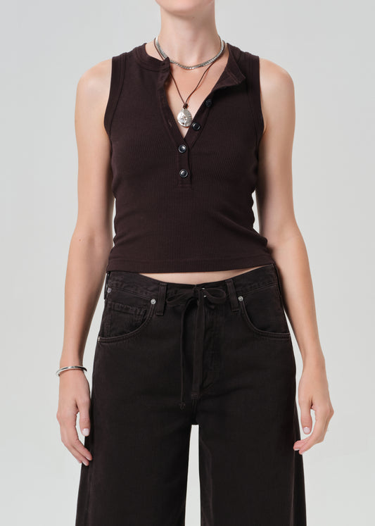 Person wearing a brown sleeveless top and brown pants on a light gray background