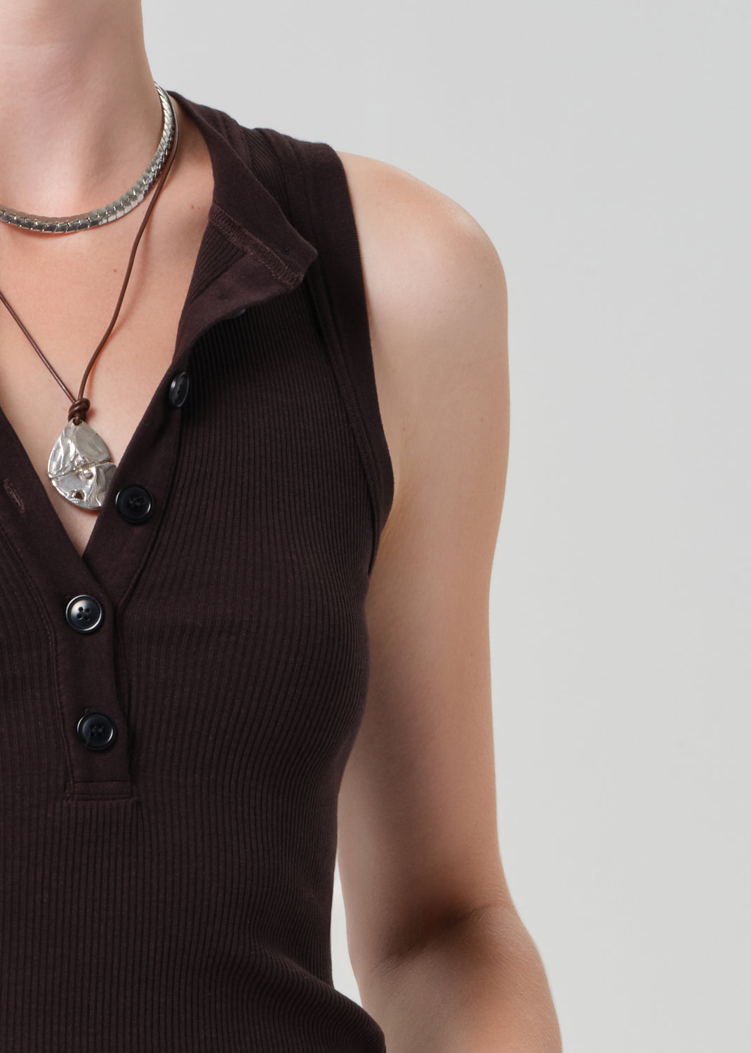 Brown sleeveless top with buttons on a plain background