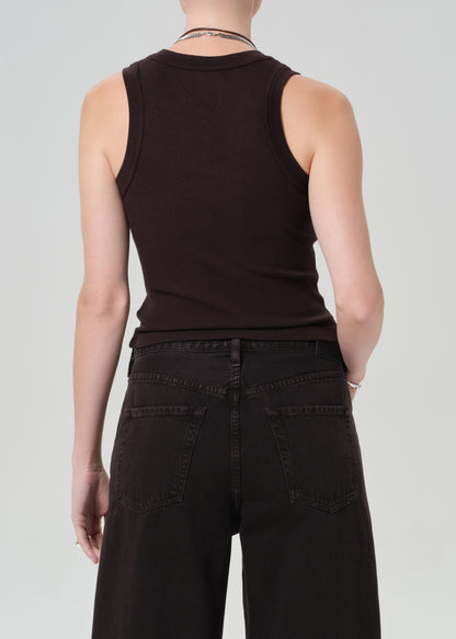 Person wearing a brown sleeveless top and brown pants on a light gray background