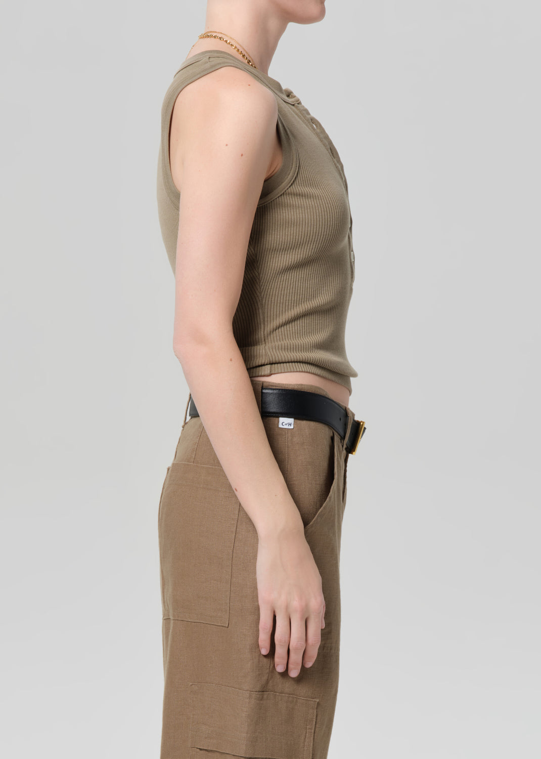 Person wearing a sleeveless brown top and cargo pants on a light gray background