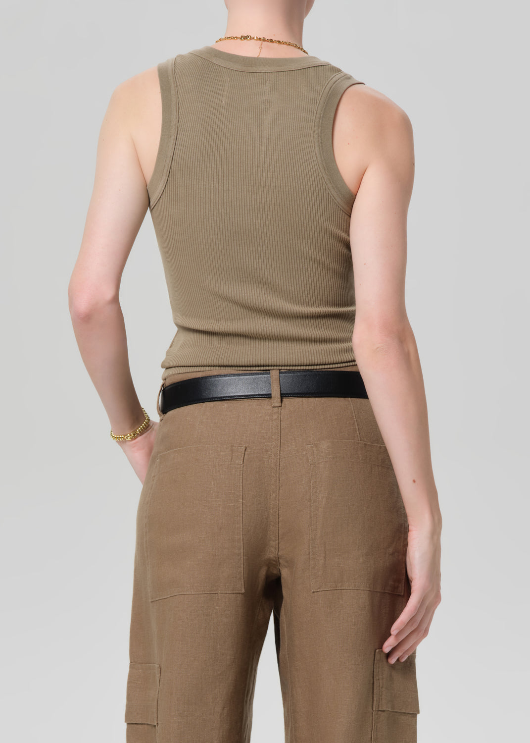 Person wearing a sleeveless brown top and cargo pants on a plain background