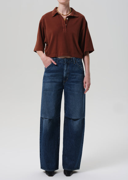 Person wearing a brown polo shirt and blue jeans on a white background