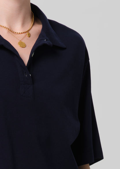 Navy blue shirt worn by a person with gold necklaces on a light gray background