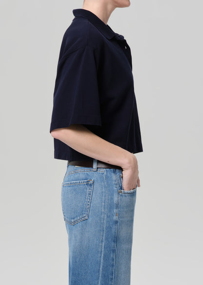 Person wearing a navy blue top and blue jeans on a light gray background