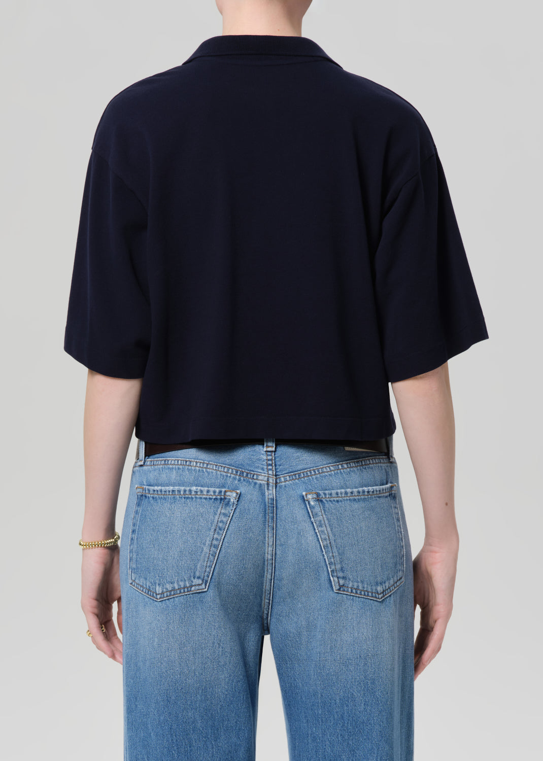 Person wearing a black t-shirt and blue jeans on a plain background