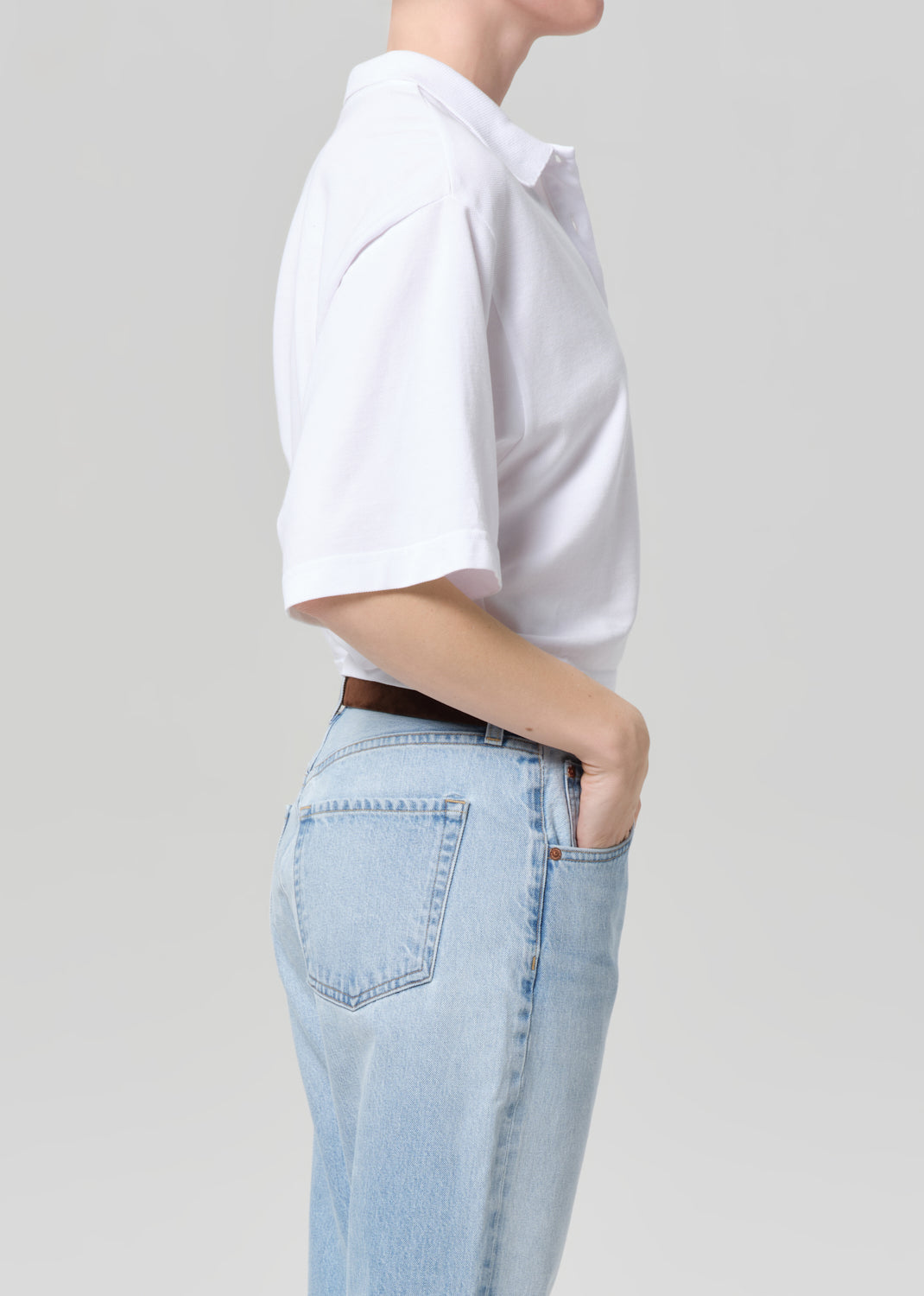 Person wearing a white t-shirt and light blue jeans on a plain background